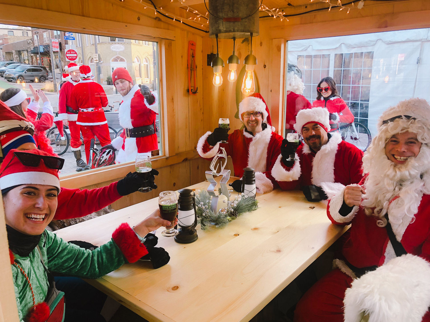 A group of friends dressed as Santa Claus toasting with a Santa Rampage bier inside a shanty